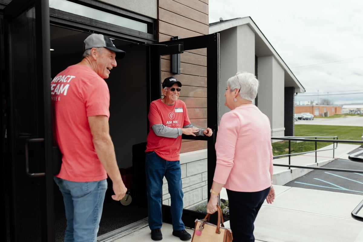 Impact Team volunteers welcoming a guest at the church doors